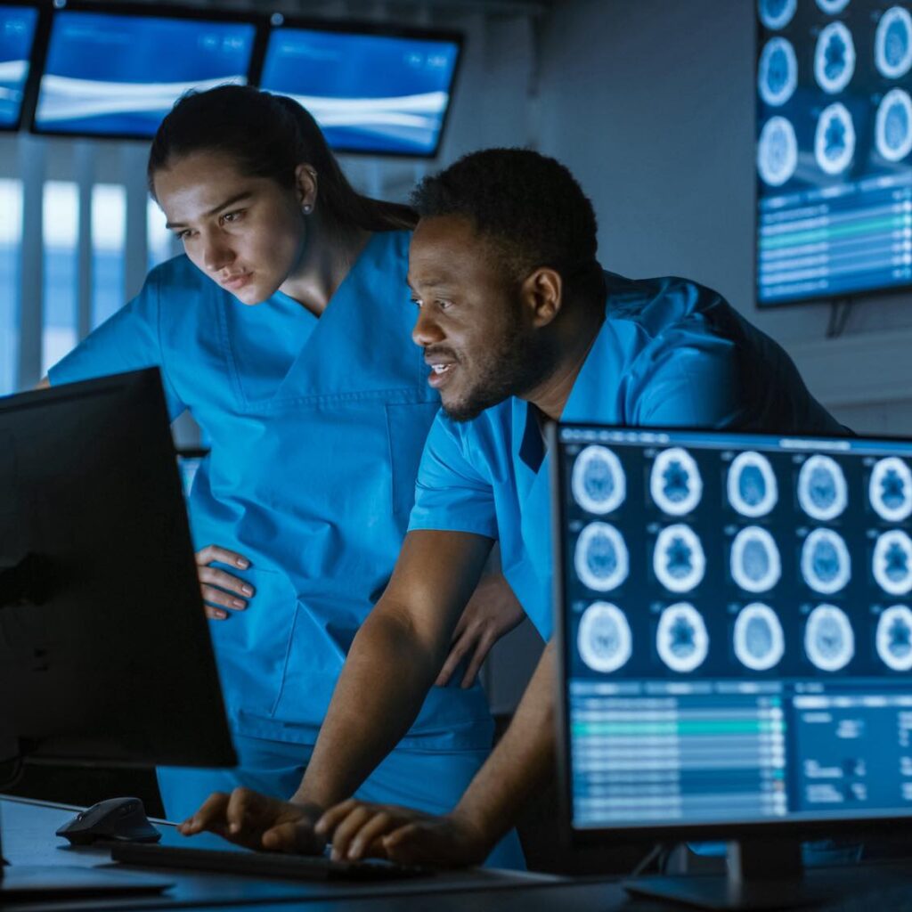 Male And Female Scientists / Neurologists, Talking And Working On A Personal Computer In Modern Laboratory. Research Medical Scientists Making New Discoveries In The Fields Of Neurophysiology, Science, Neuropharmacology. Understanding Human Brain.