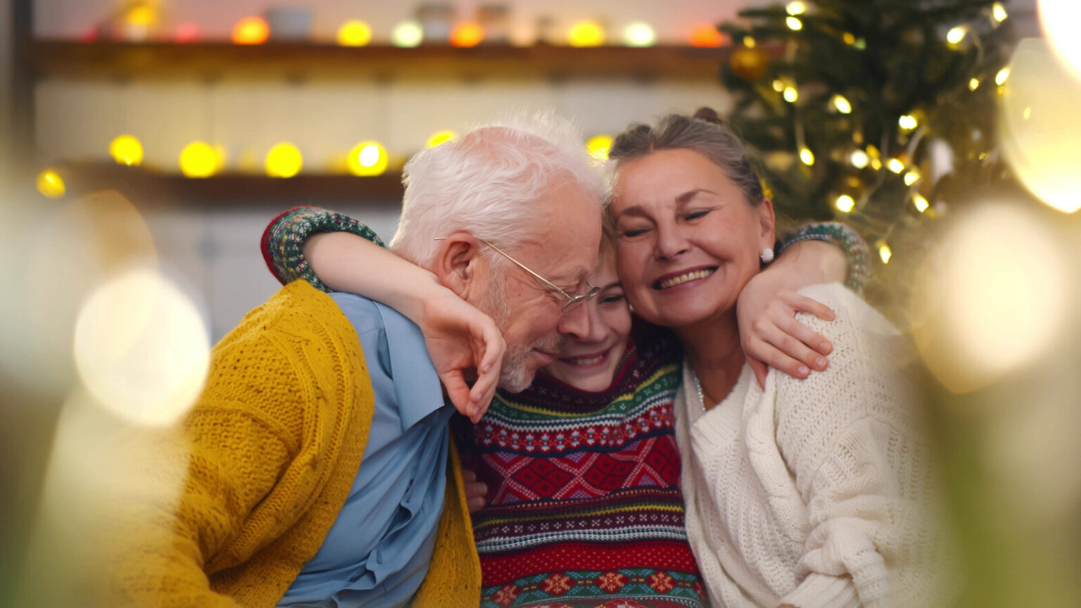 Smiling Grandparents And Grandson Sitting On Couch At Home